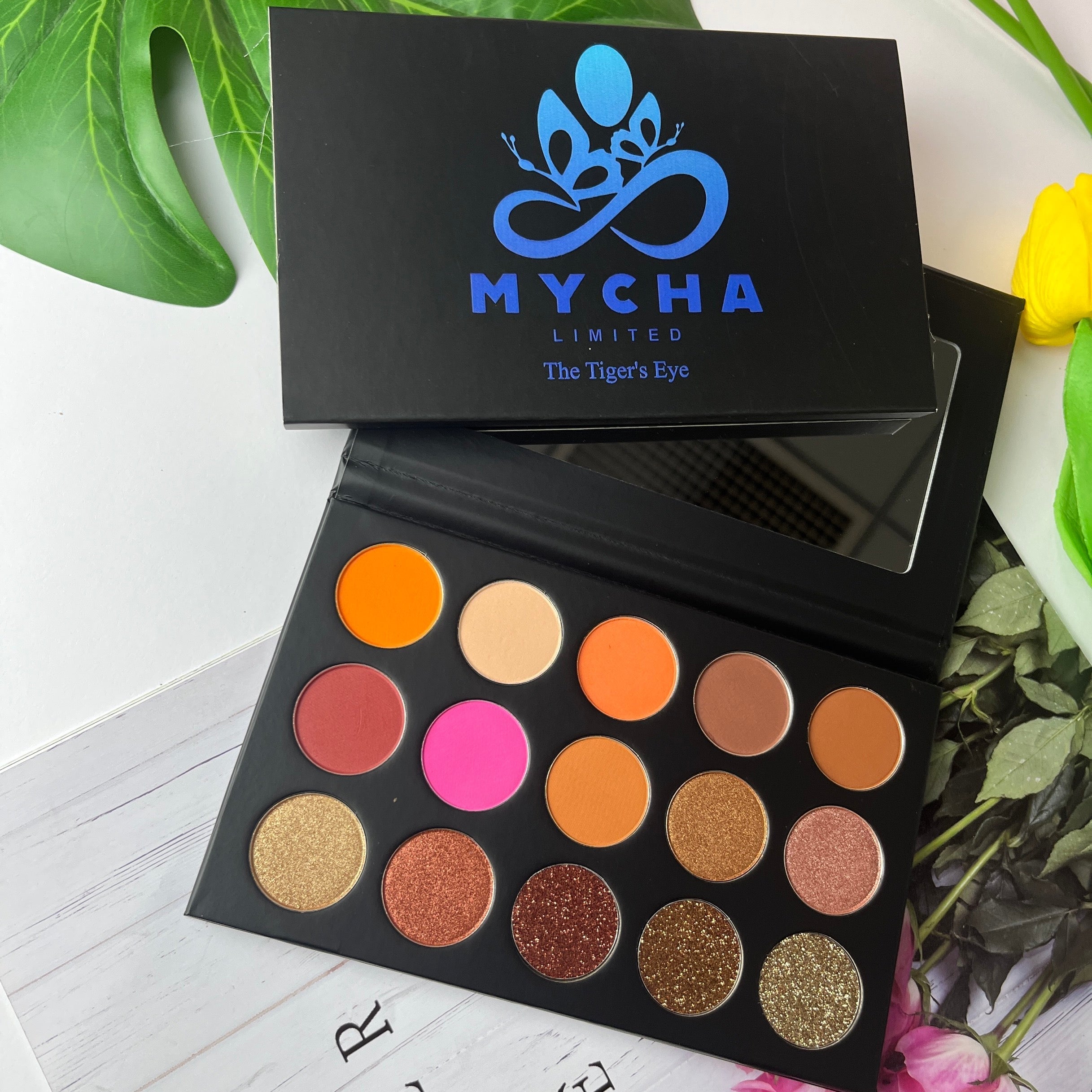 Tiger's Eye eyeshadow palette with natural brown, matte, shimmer, and glitter shades in a black case with mirror.