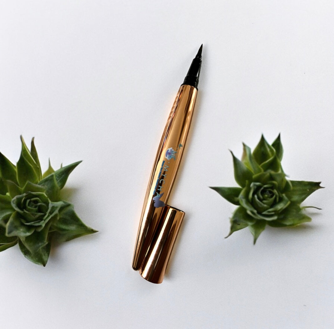Waterproof 4D mascara and liquid eyeliner combo with gold packaging placed between two green succulents