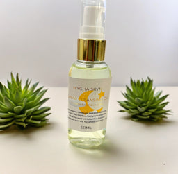 Lunar Cleansing Oil bottle with pump dispenser on white surface surrounded by green succulents